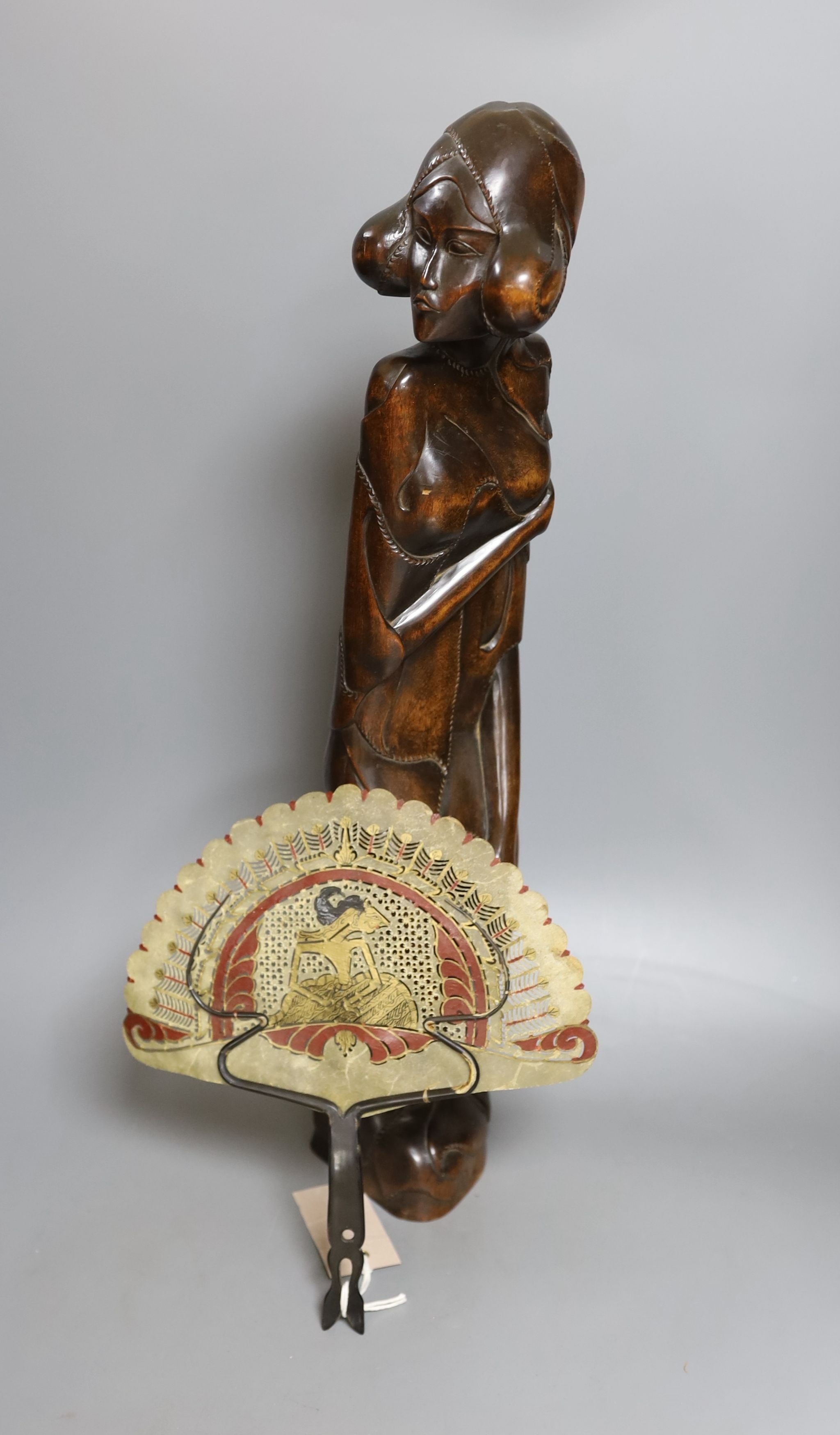 A Burmese carved hardwood figure, 51.5cm tall, and a Burmese horn and animal-bladder fan